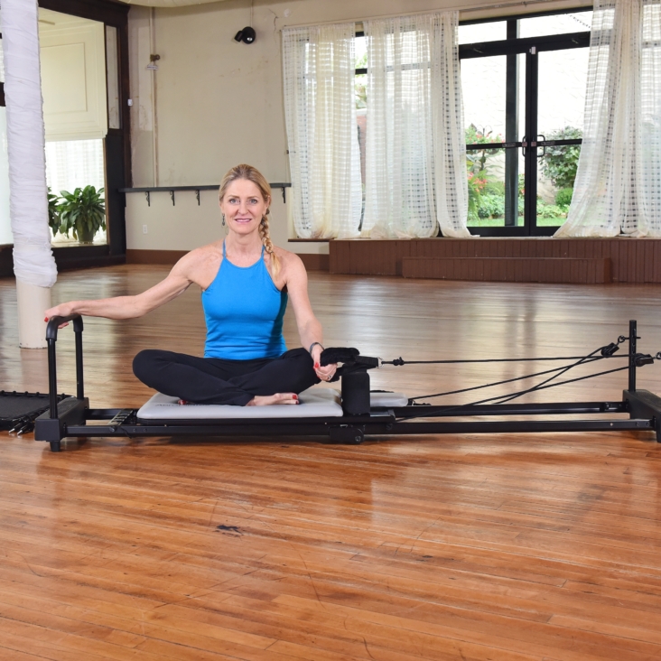 Middle age woman sitting on Aeropilates Exercise Bundle Kit.
