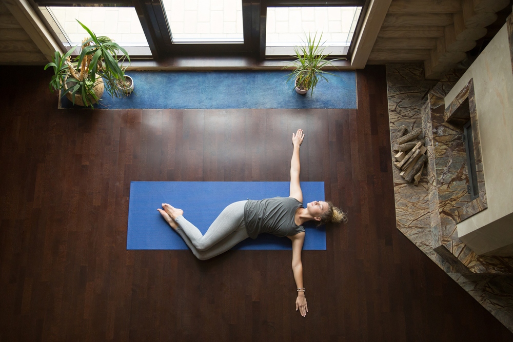 A woman lies on her back with knees to the side for a lower trunk rotation.